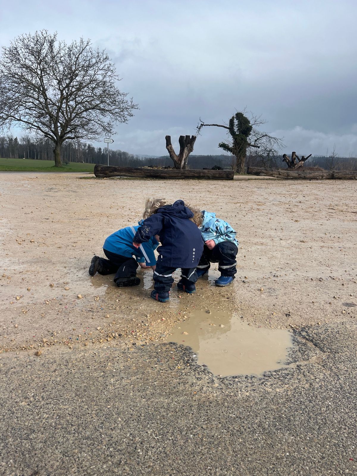 Kinder spielen draussen an einer Pfütze