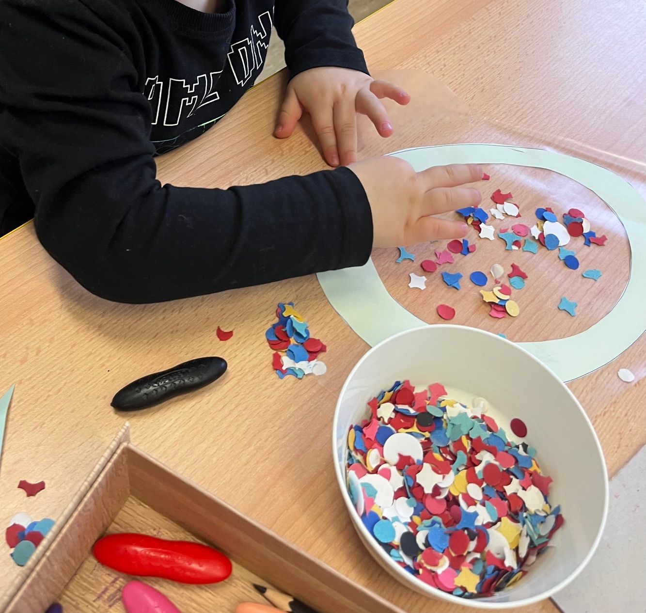 Kind bastelt mit buntem Konfetti