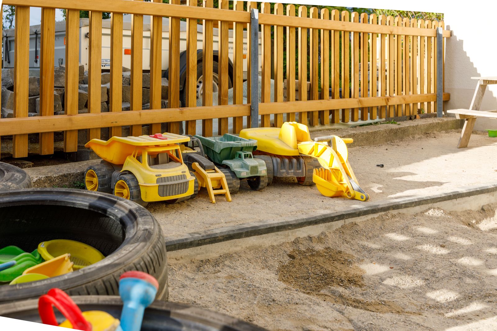 Sandkasten mit Baggern und Spielfahrzeugen im Garten der Kita Wisebärg