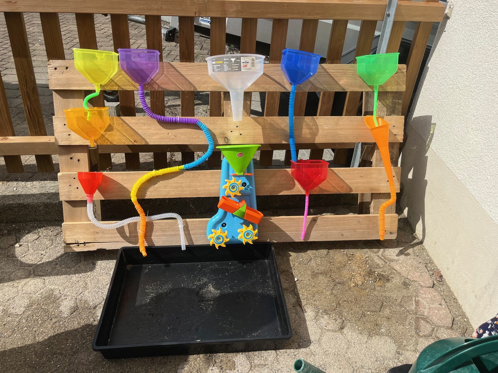 Wasserspielwand mit bunten Trichtern im Garten