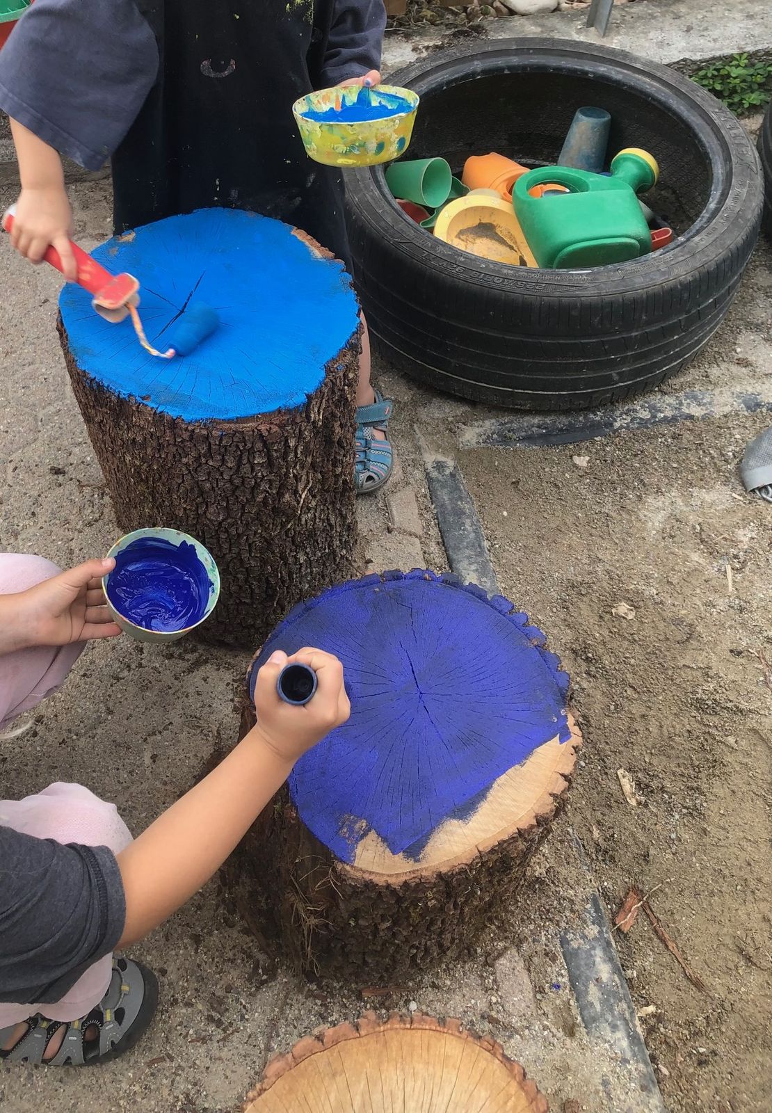 Kinder malen Baumstämme blau an