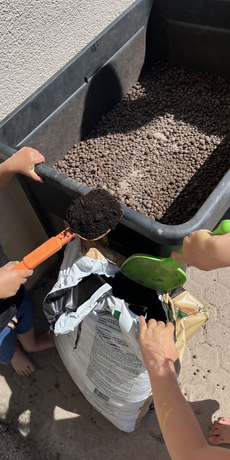 Kinder befüllen ein Hochbeet mit Erde