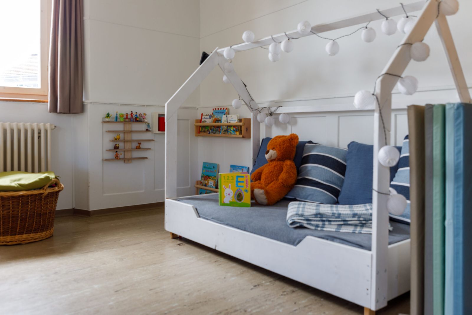 Kinderbett im Häuschen-Stil mit Kuscheltieren im Ruhebereich der Kita