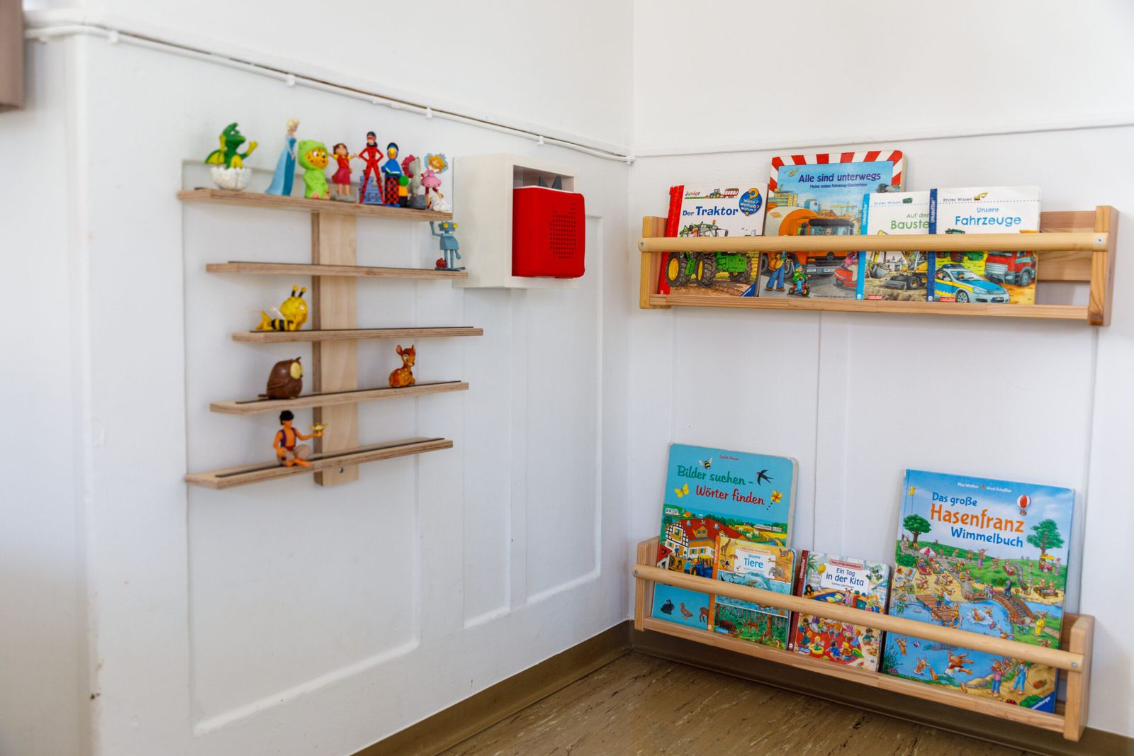 Wandregale mit Bilderbüchern und Spielfiguren im Gruppenraum