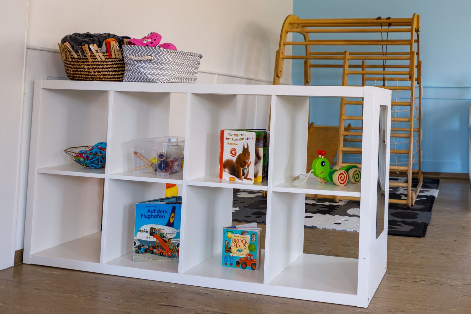 Regal mit Büchern und Holzspielzeug vor dem Klettergerät