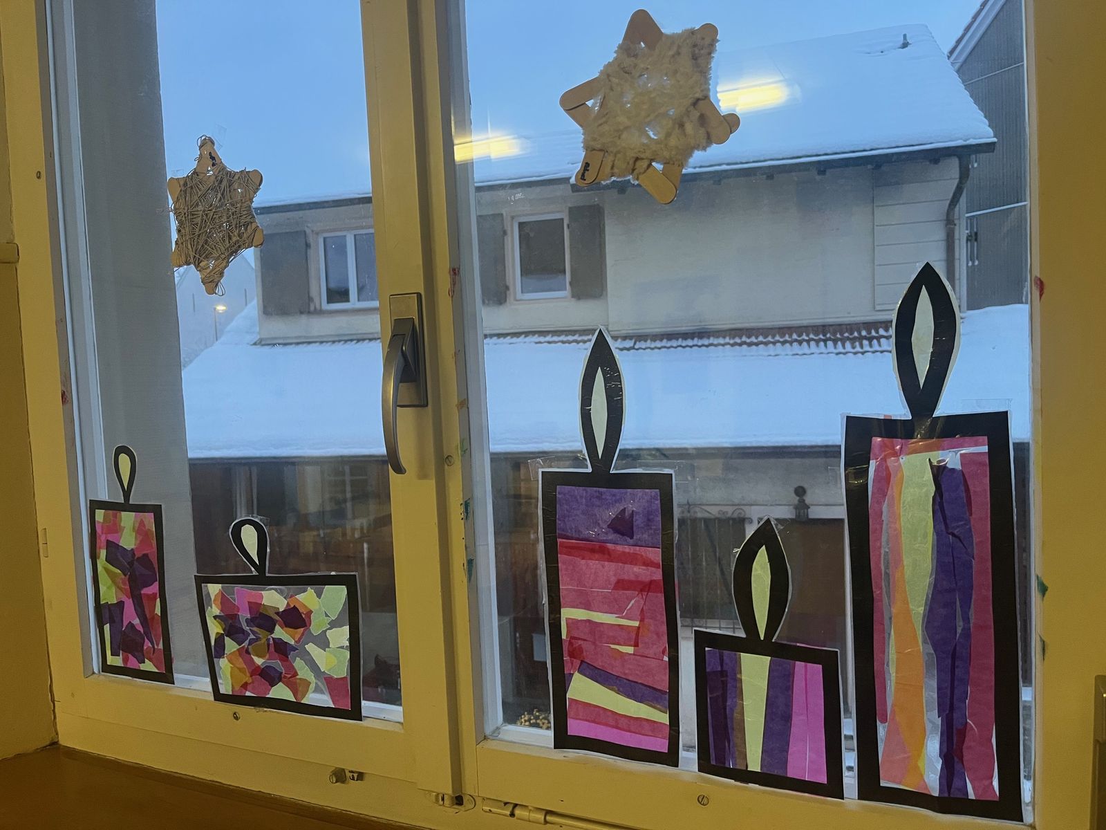 Fenster mit gebastelten Kerzen und Sternen